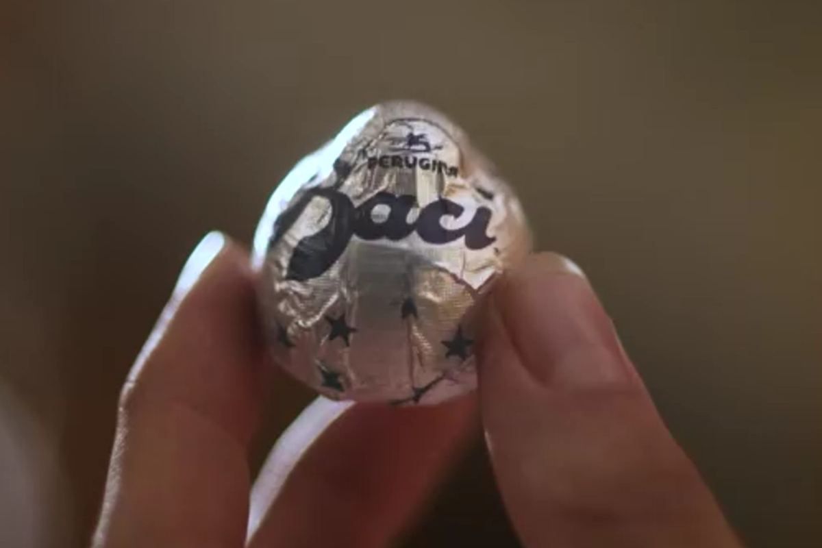 una mano stringe tra le dita un bacio perugina